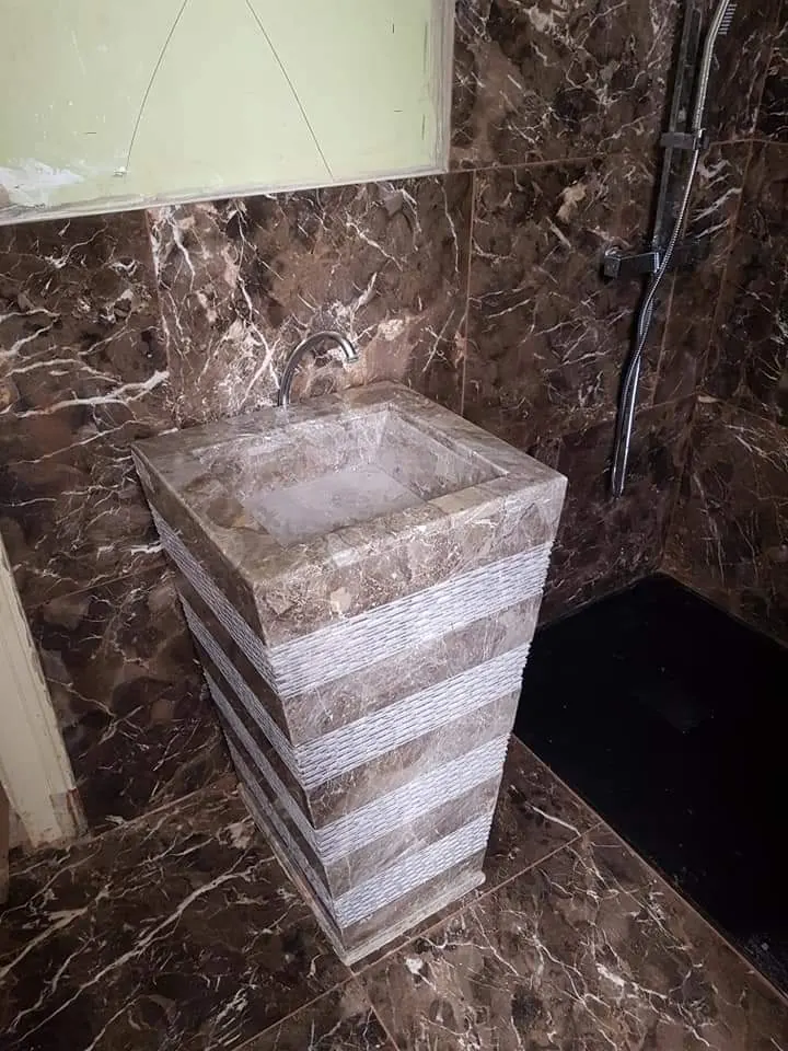 Vasque colonne à bandes de marbre devant un mur en marbre Emperador, réalisation Dekorenov