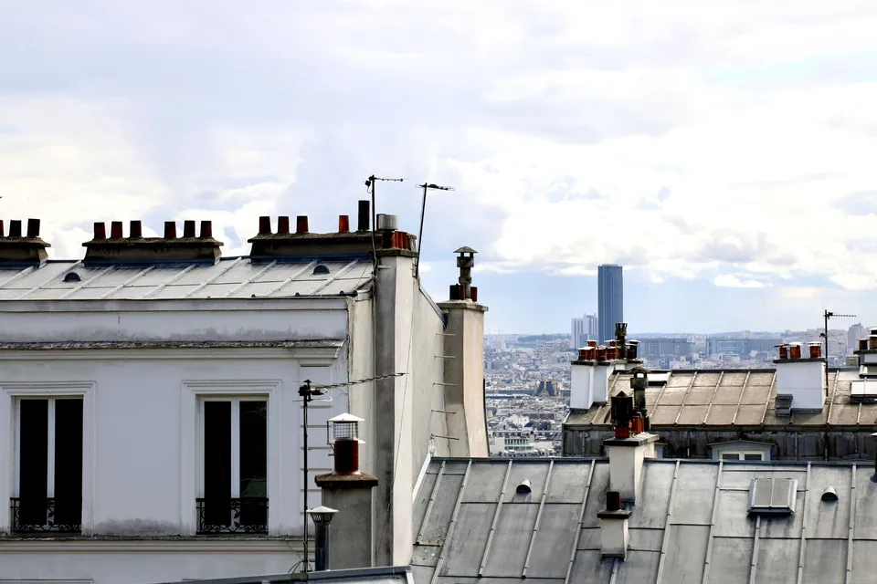 Toits parisiens en zinc et cheminées, avec la ville en arrière-plan