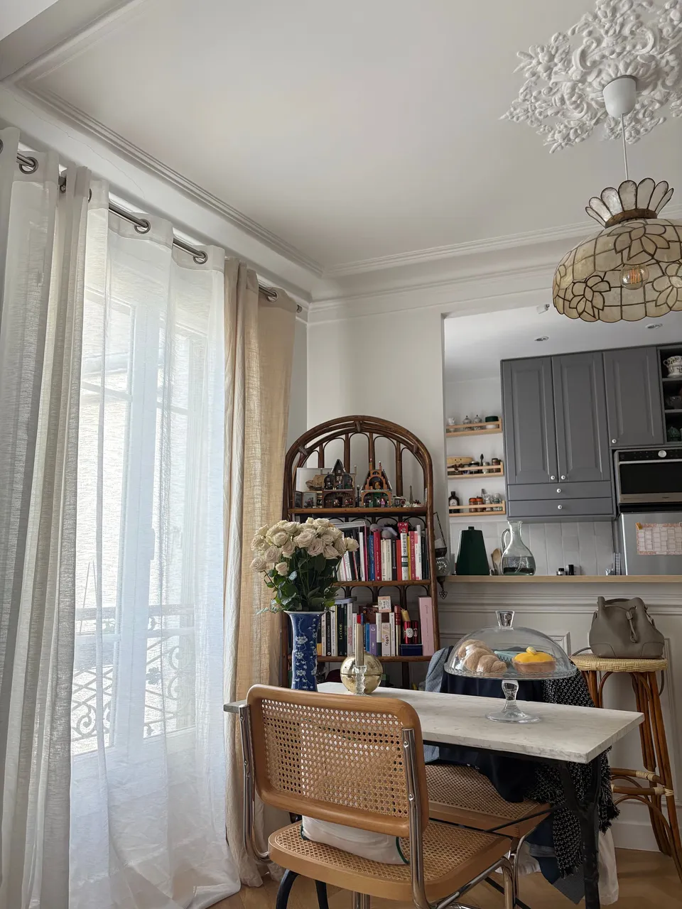 Appartement parisien à moulures avec cuisine ouverte et table à plateau de marbre blanc