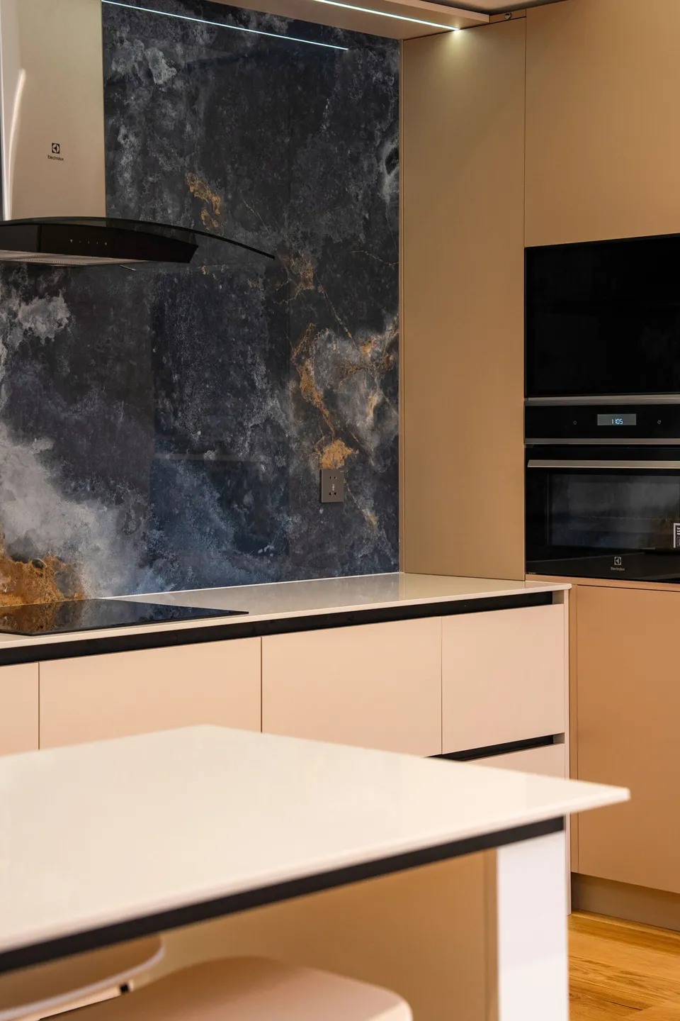Cuisine moderne avec crédence en grande plaque de marbre sombre veiné et îlot blanc